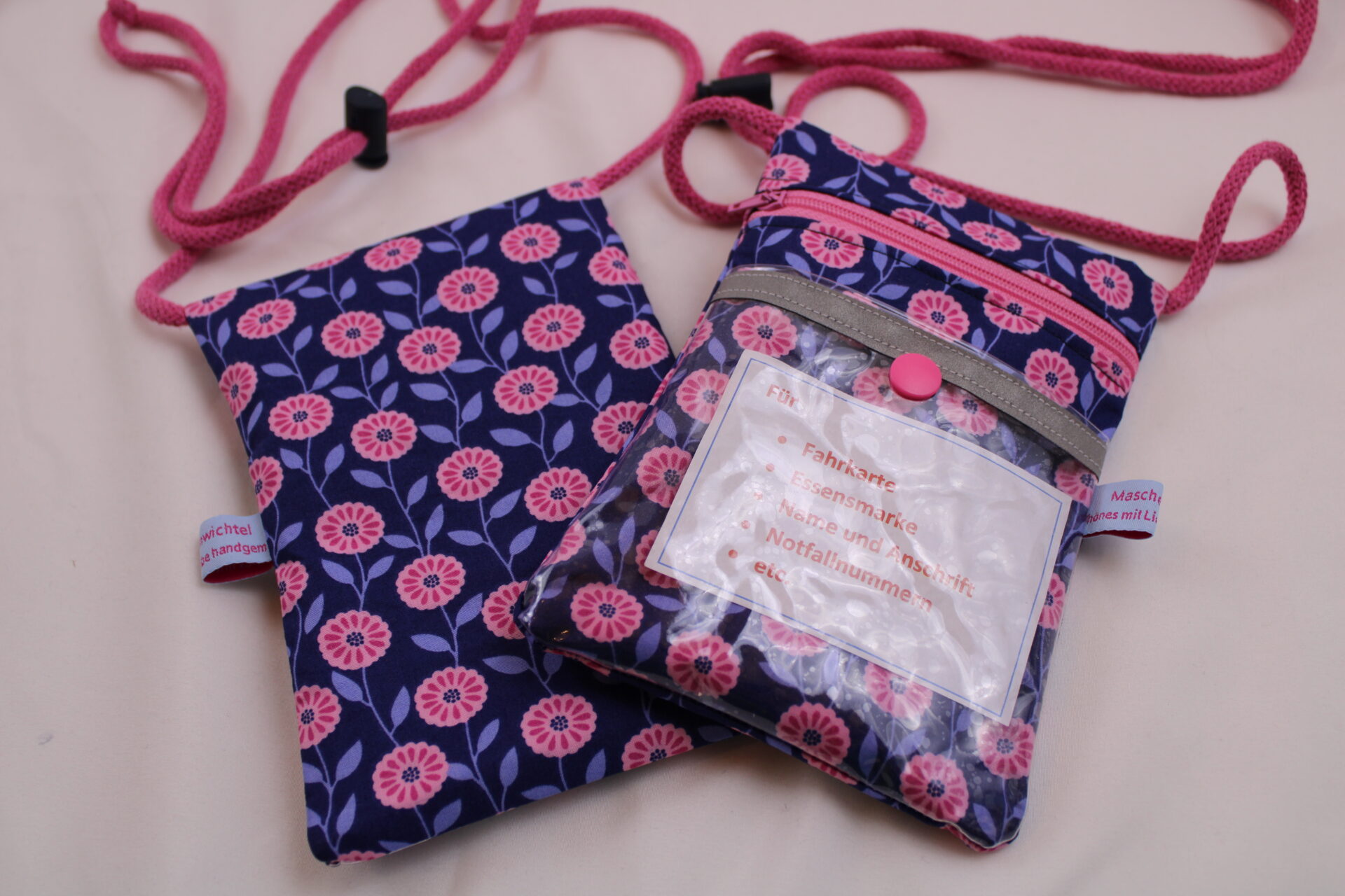 Brustbeutel Kinder Klarsichtfach Rosa Blüten auf Blau (1) BRUSTBEUTEL / Umhängetäschchen für Kinder "Rosa Blüten" mit Klarsichtfach mit Reflektorstreifen; Geldbörse, Fahrkartentasche, Kindergeldbeutel